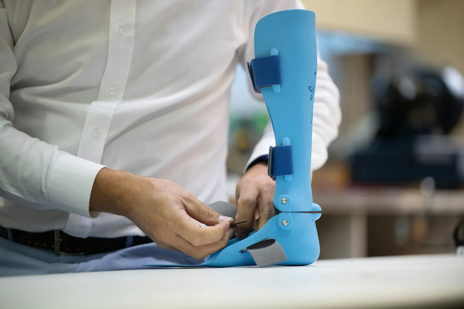 Hands adjusting the strap of a custom ankle-foot orthosis